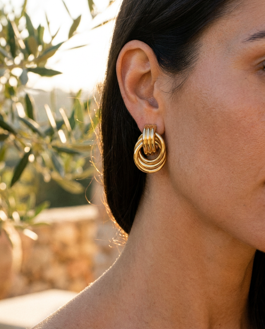 Delphine knotted double hoop earrings worn, close crop on the ear in golden hour light
