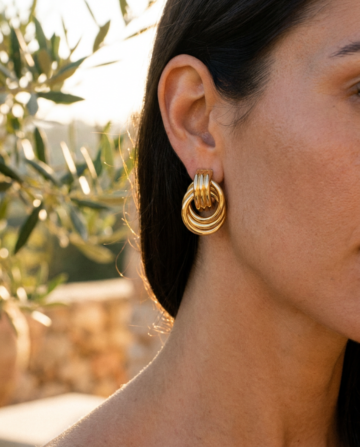 Delphine knotted double hoop earrings worn, close crop on the ear in golden hour light